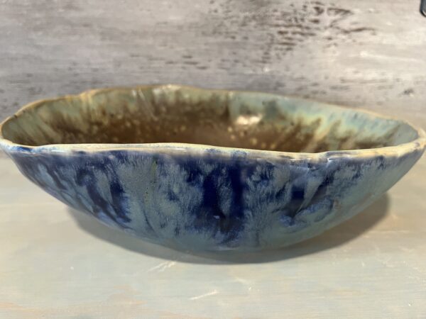 Organic stoneware bowl with teal glaze on the exterior and brown and cream glaze on the interior.