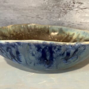 Organic stoneware bowl with teal glaze on the exterior and brown and cream glaze on the interior.